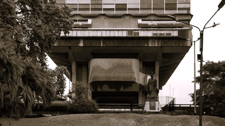 Raised concrete building dominating a field